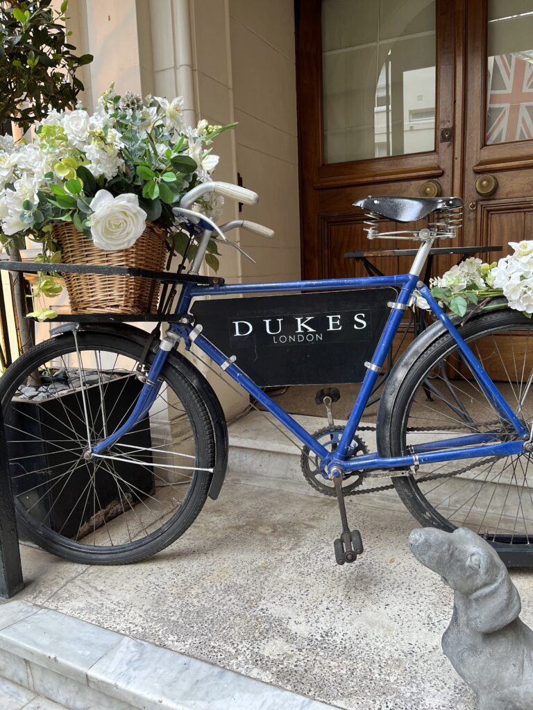 Dukes Bar London Mayfair Hotel, bicycle with potted flowers in front of Dukes bar sign