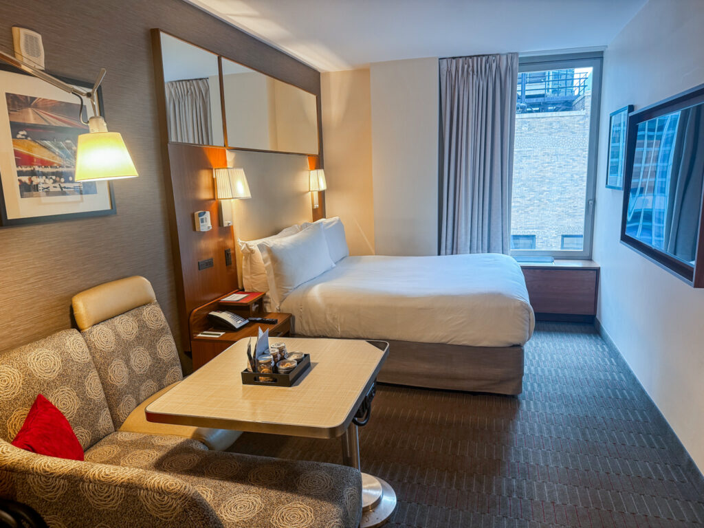 best hotels in nyc under 500, photo showing hotel room with queen bed and workstation at Club Quarters Grand Central