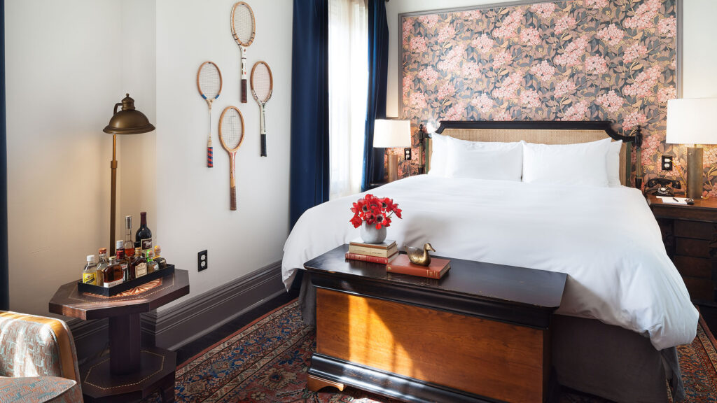 Best NYC Hotels Under 500, The High Line Hotel, Deluxe King Room with floral wallpaper, tennis racquets on wall, wood bed